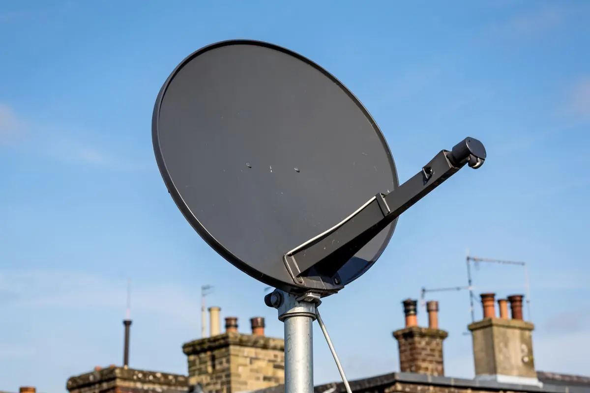 Large dark satellite dish on a London rooftop aligned for Hotbird foreign-language channels