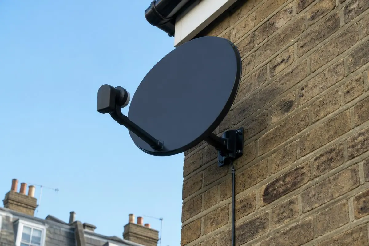 Modern black satellite minidish neatly installed on a London brick wall for Sky and Freesat