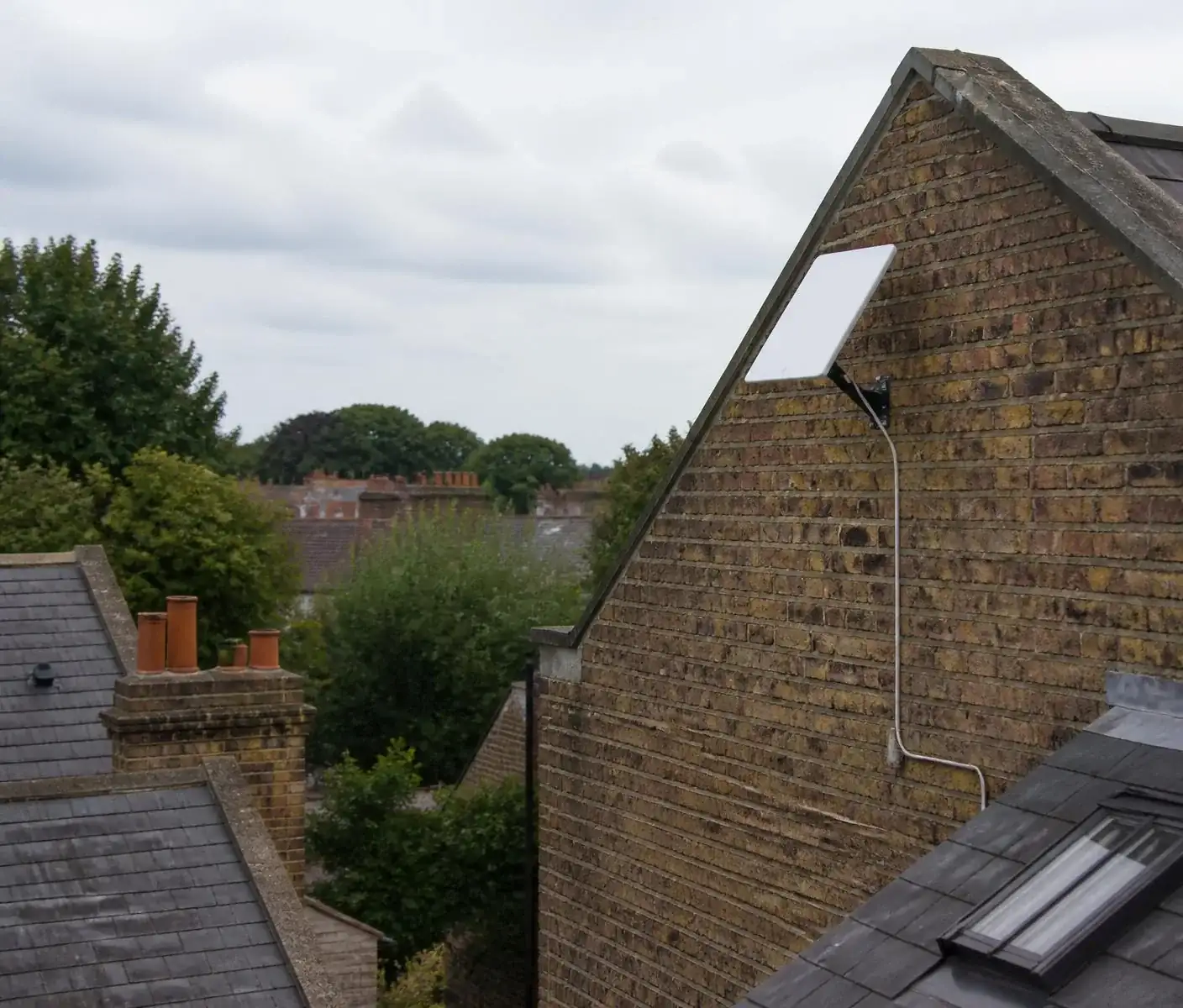 White flat-panel satellite internet dish mounted on a London rooftop