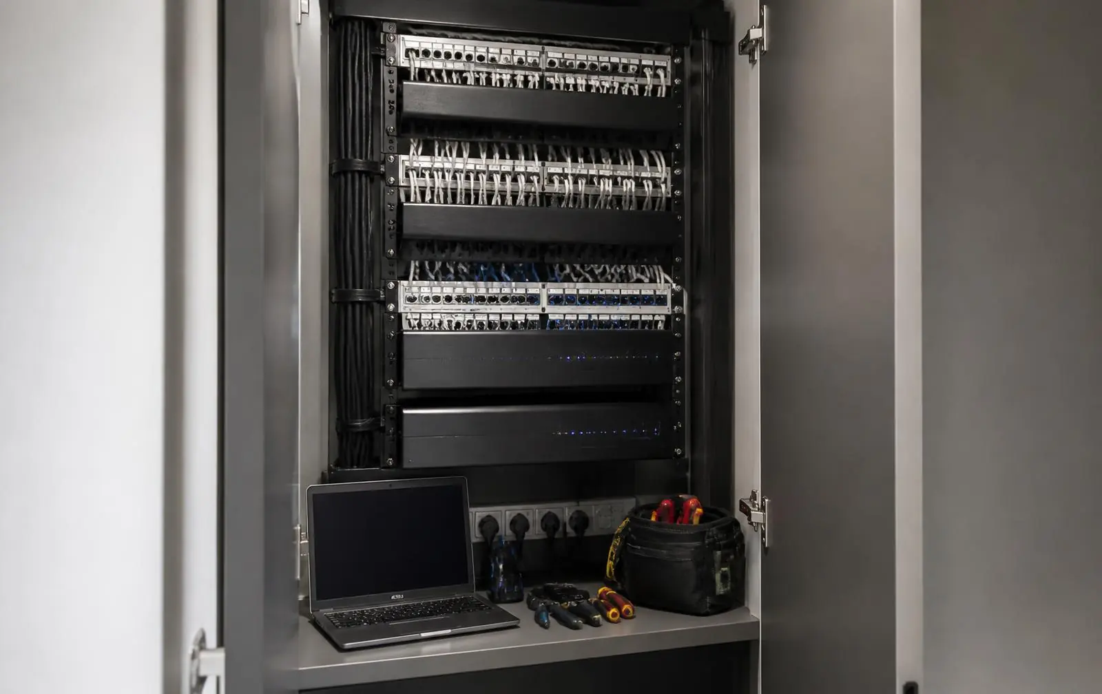 Engineer with a laptop servicing a smart home equipment rack